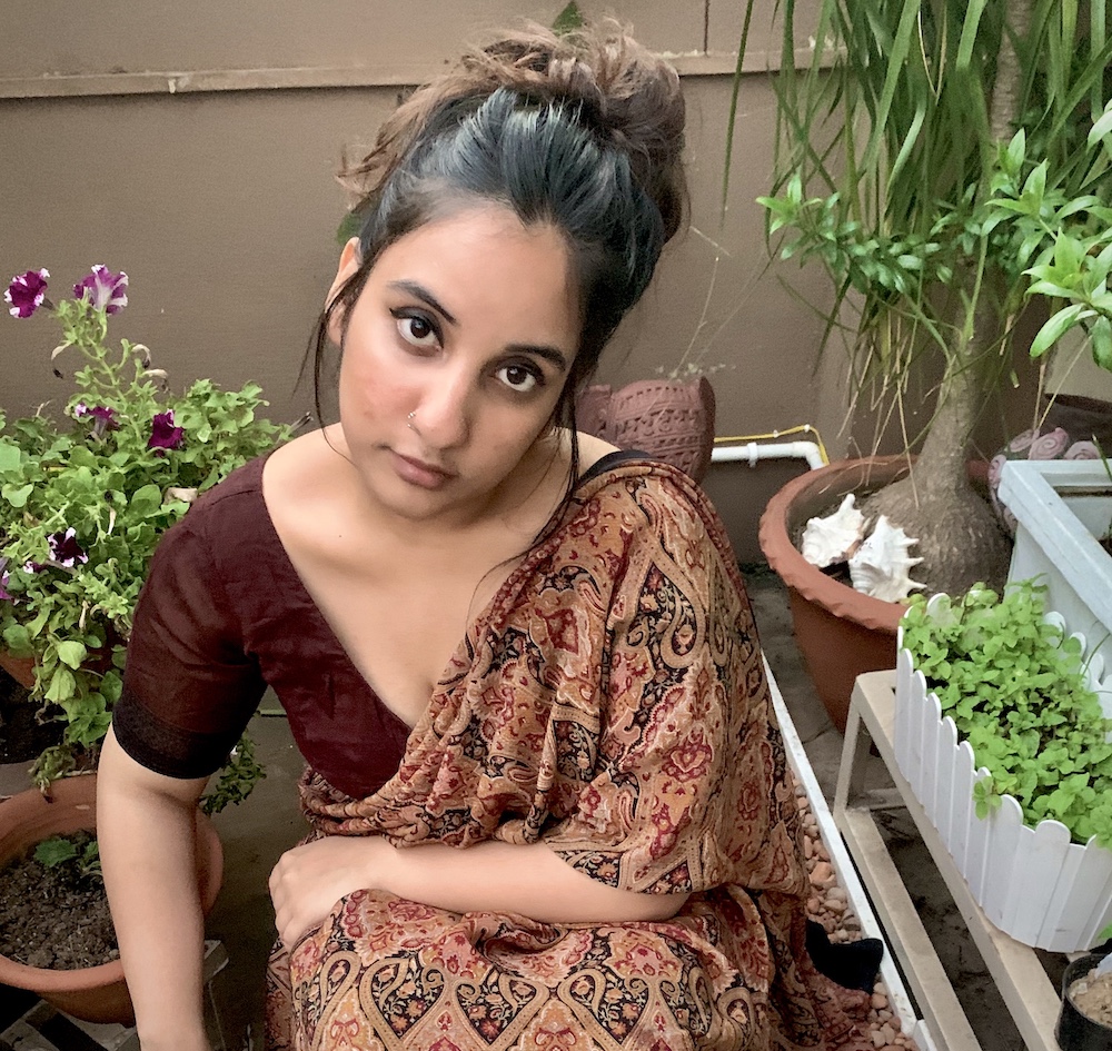 Bidisha wears saree and looks up to the camera surrounded by plants